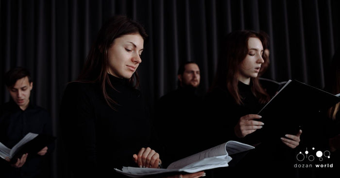 Choir members reading sheet music during a winter concert rehearsal, exploring repertoire beyond traditional Western choral classics.